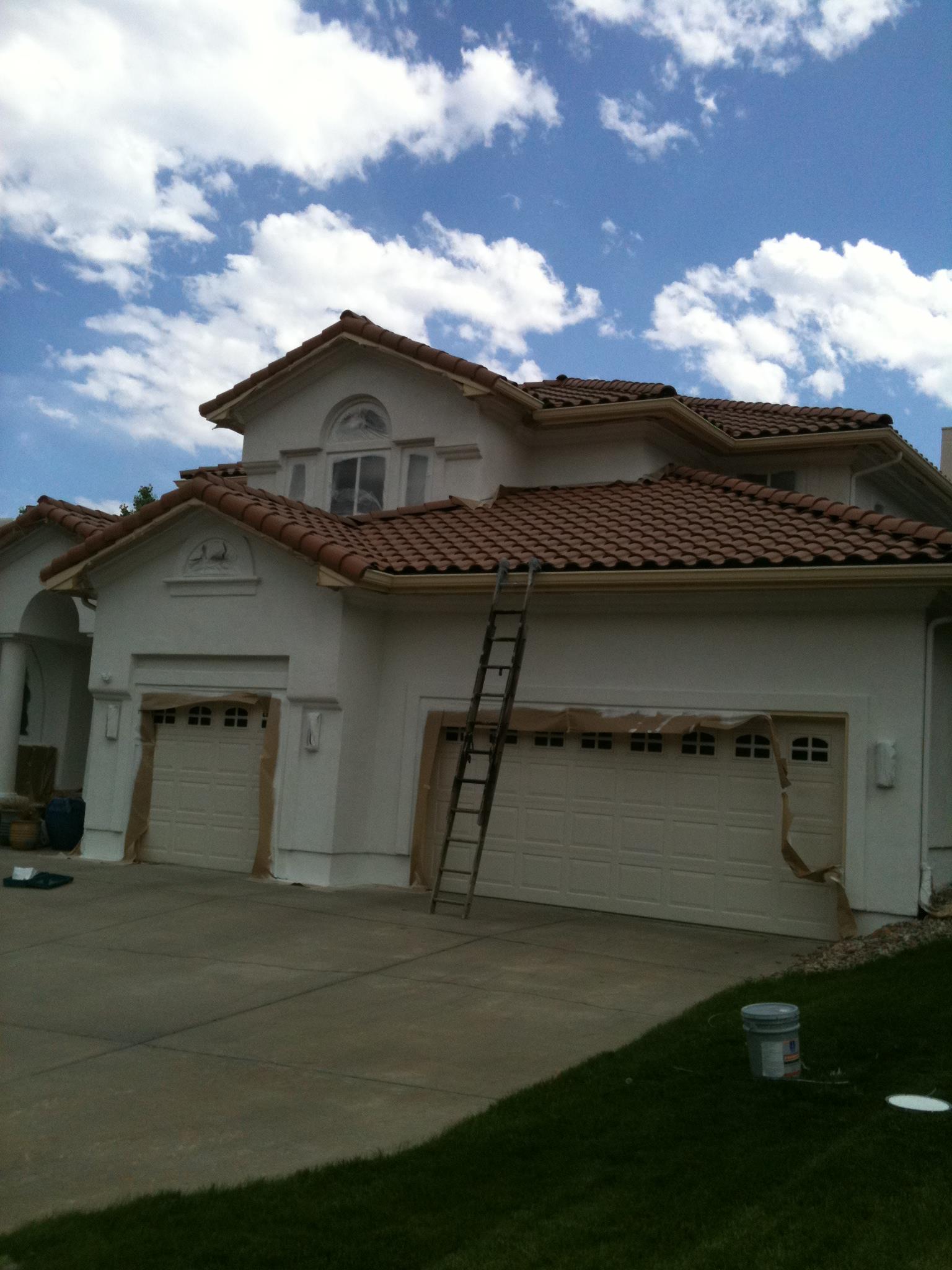 Two-story stucco home with tile roof and ladder on site
