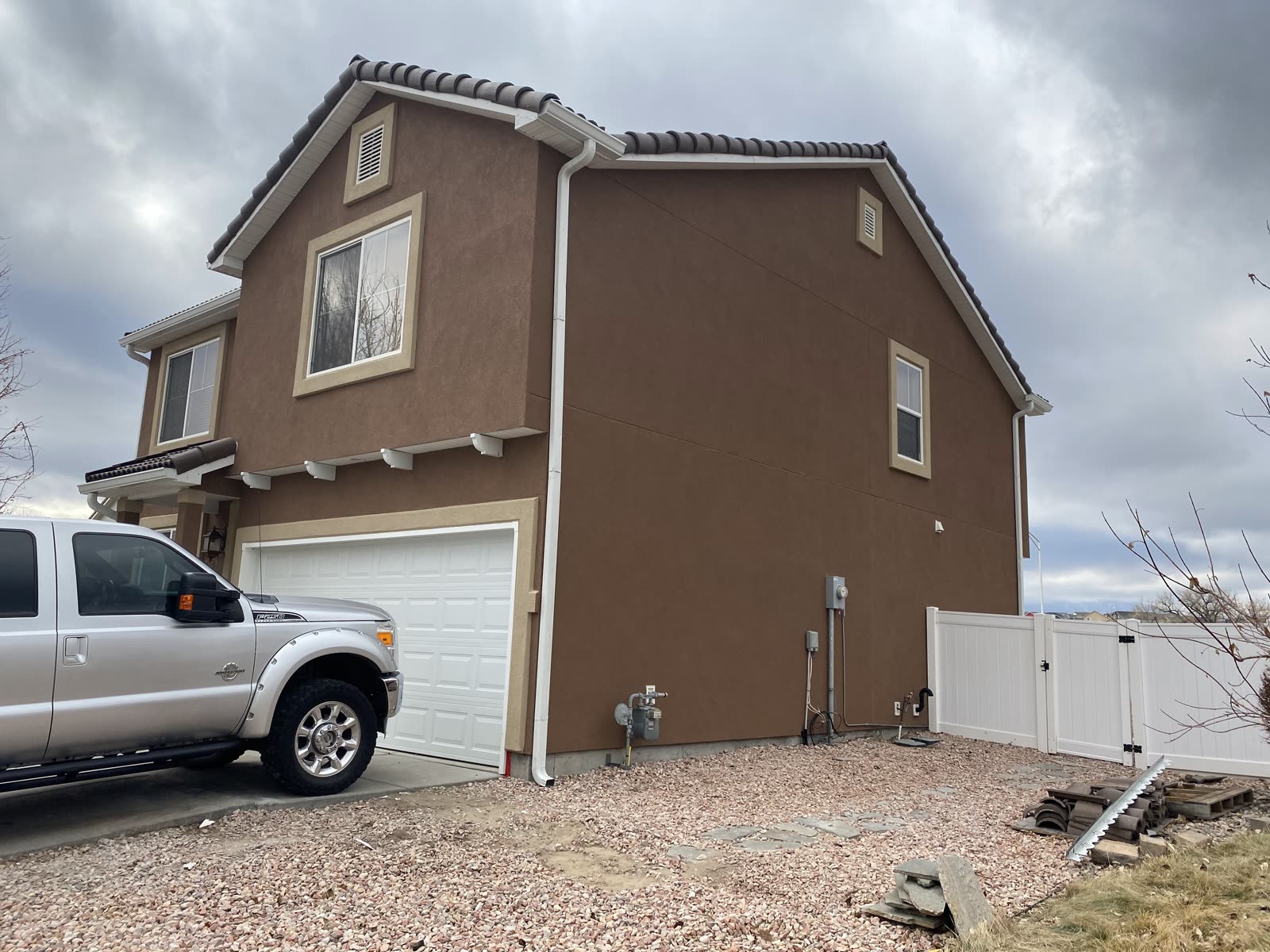 Two-story tan stucco home with bright trim and truck on site